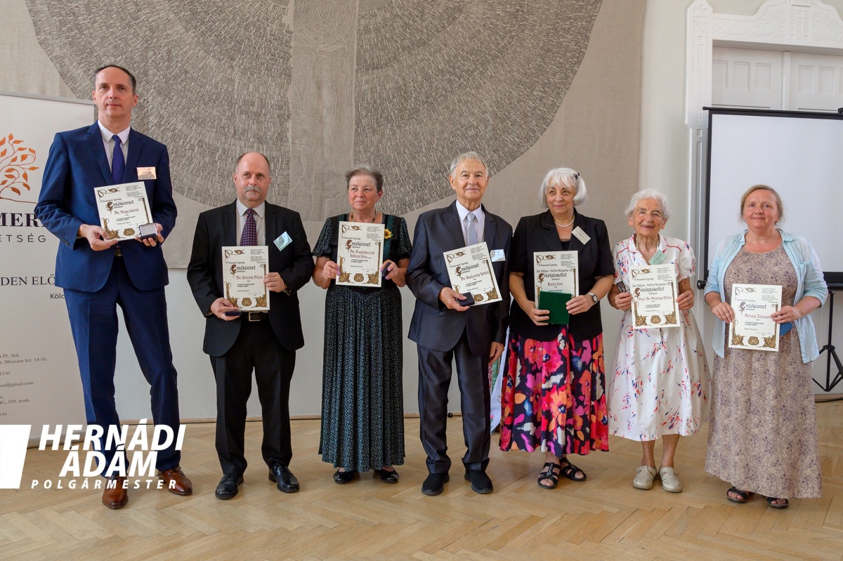 Dr. Gyarmati Béla (a fenti képen balra), az intézmény Egészség- és Sporttudományi Karának egyetemi docense a dr. Pintér Sándor belügyminiszter által adományozott miniszteri elismerő oklevelet vehette át dr. Takács Péter egészségügyi államtitkártól (a fenti képen jobbra) a Belügyminisztériumban tartott Semmelweis-napi ünnepségen.  02  A Honismereti Szövetség az Esztergomban megrendezett LI. Országos Honismereti Akadémia programja részeként a Széchenyi István Egyetem három munkatársának honismereti-helytörténeti tevékenységét is elismerte. A nagy múltú civil szervezet dr. Simonik Péternek (a fenti képen balról a második), az Apáczai Csere János Pedagógiai, Humán- és Társadalomtudományi Kar Szociális Tanulmányok és Szociológia Tanszéke egyetemi docensének Honismeretért emlékérmet, míg dr. Lanczendorfer Zsuzsannának (a lenti képen a bal szélen), a kar Bölcsészettudományi és Humánerőforrás-fejlesztési Tanszéke egyetemi docensének, valamint Biczó Zalánnak, az Egyetemi Könyvtár és Levéltár jogi kari szakkönyvtára könyvtárosának Honismereti Munkáért emléklapot ítélt oda.  03  Fotók: Széchenyi István Egyetem,  Hernádi Ádám esztergomi polgármester Facebook-oldala (2. kép) Széchenyi István Egyetem